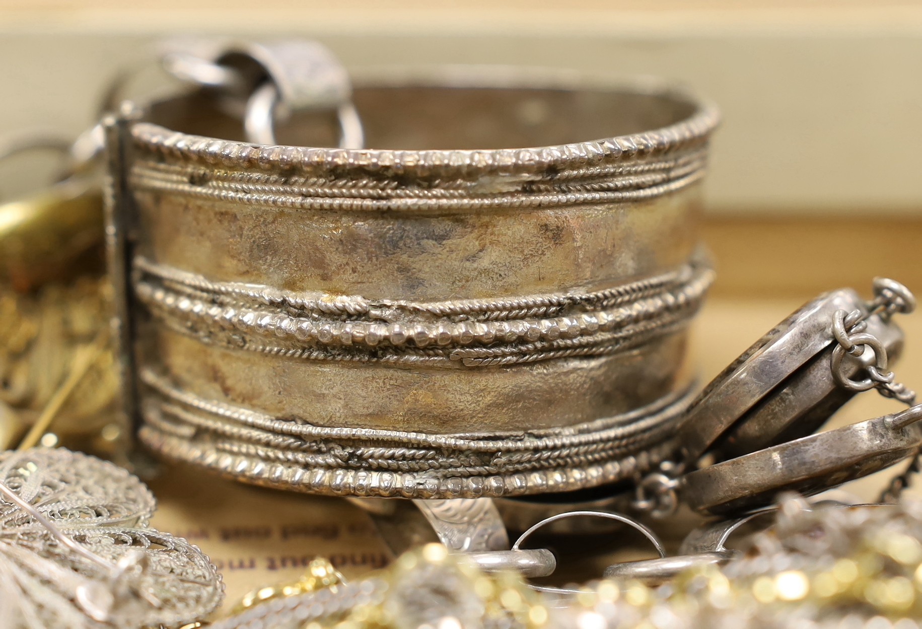 A collection of assorted 19th century and later jewellery, including Middle Eastern white metal canister in chain, yellow metal eat studs and other items including rings, toothpick, necklaces, silver stamp case etc.